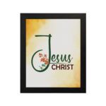 Jesus Christ text in green script with red floral accents on a glowing yellow-orange background, framed in black. hung on the wall in a black frame