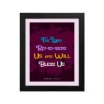 Infidu Bible Wall Art with the text The Lord Remembers Us and Will Bless Us in blue, yellow, and white on a purple background. hung on the wall in a black frame