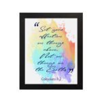 Bible wall art featuring Colossians 3:2 in cursive text on a colorful rainbow background. hung on the wall in a black frame