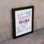 Infidu You Are The Temple Of God 1 Corinthians 3:16 Bible Wall Art with watercolor flowers and bold scripture design displayed on the wall in a black frame