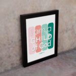 Infidu I Am A Child Of God John 1:12 Christian Wall Art with modern pink and green gradient design on a playful background. displayed on the wall in a black frame