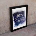 Bless The Lord O My Soul Psalm 103:1 Christian wall art with white text on a deep blue watercolor background. displayed on the wall in a black frame