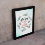 Proverbs 4:7 Bible verse wall art with green leaf wreath and red flowers, perfect for Christian home decor. displayed on the wall in a black frame