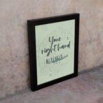 Your Right Hand Upholds Me Psalm 63:8 Christian wall art with dark gray text and light green floral elements on a pale green displayed on the wall in a black frame background.