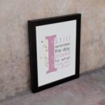 Christian wall art featuring the phrase 'I Still Remember The Days I Prayed For What I Have Now' with pink and gray text and gold flowers. displayed on the wall in a black frame