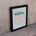 Wisdom Proverbs 2:6 Christian wall art with teal and red text on a mint green background in a black frame. displayed on the wall in a black frame