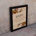 Proverbs 2:6 Christian Wall Art with "Wisdom" text, floral accents, and a beige background displayed on the wall in a black frame