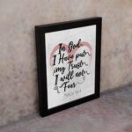 In God I Have Put My Trust, I Will Not Fear Psalm 56:4 Bible Verse Wall Art with pink watercolor arc and black frame. displayed on the wall in a black frame