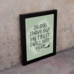 In God I Have Put My Trust, I Will Not Fear Psalm 56:4 bold Christian wall art with green background and brushstroke lettering displayed on the wall in a black frame