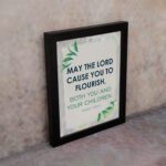 Infidu Christian wall art featuring Psalm 115:14 with bold text, green highlights, and leaf designs on a light gray background. displayed on the wall in a black frame