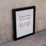 Christian wall art with the verse The Grass Withers, The Flower Fades But The Word Of Our God Will Stand Forever Isaiah 40:8. displayed on the wall in a black frame