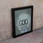 Isaiah 40:8 Christian wall art with light gray and white text on a muted blue background, featuring "GOD" in bold letters. displayed on the wall in a black frame