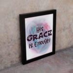 His Grace Is Enough Christian wall art with bold dark purple text and a soft gradient background in pink, purple, and blue. displayed on the wall in a black frame