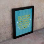 Christian wall art with Proverbs 31:25 verse in bold yellow text on a dark blue background with floral accents displayed on the wall in a black frame