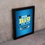 Infidu Dream Big Work Hard Make It Happen wall art with a blue background white, yellow, and black text, and a black frame on the wall. Inspiring decor for home offices and workspaces.