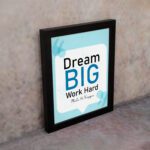 Infidu Dream Big Work Hard Make It Happen wall art with a sky blue and white background and sky blue and black text and black frame on the wall. Inspiring decor for home offices and workspaces.