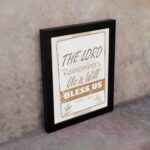 Infidu The Lord Remembers Us And Will Bless Us Psalm 115:12 Bible wall art with elegant text and plant border. displayed on the wall in a black frame