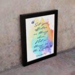 Bible wall art featuring Colossians 3:2 in cursive text on a colorful rainbow background. displayed on the wall in a black frame