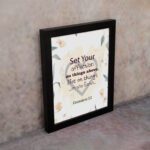 Colossians 3:2 Bible verse wall art with floral design and bold lettering, featuring the words Set Your Affection on Things Above. displayed on the wall in a black frame