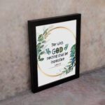 Wall art featuring the quote With God Nothing Shall Be Impossible from Luke 1:37, surrounded by a golden frame and green leaves. displayed on the wall in a black frame