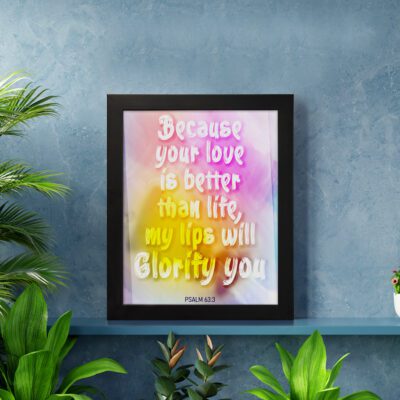 Christian wall art with Psalm 63:3, bold text in playful font, vibrant yellow, pink, and purple gradient on a warm background with a black frame. displayed on the wall in a black frame