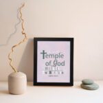 You Are The Temple of God 1 Corinthians 3:16 Christian Wall Art with soft pink background and elegant grey text. displayed on the wall in a black frame