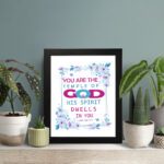 Infidu You Are The Temple Of God 1 Corinthians 3:16 Bible Wall Art with watercolor flowers and bold scripture design displayed on the table in a black frame