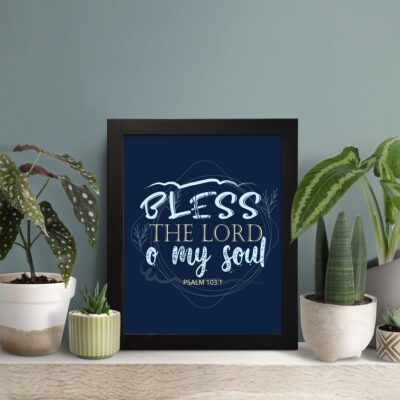 Infidu wall art featuring Bless The Lord O My Soul Psalm 103:1 in gold and white text on a dark blue background with decorative leaves. displayed on the table in a black frame