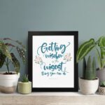 Proverbs 4:7 Christian wall art with elegant script and floral design, featuring Getting Wisdom Is The Wisest Thing You Can Do. displayed on the table in a black frame