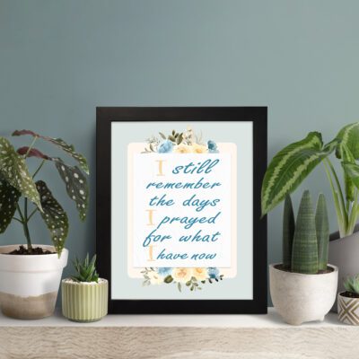 Christian wall art with the quote I Still Remember The Days I Prayed For What I Have Now surrounded by floral decorations. displayed on the table in a black frame