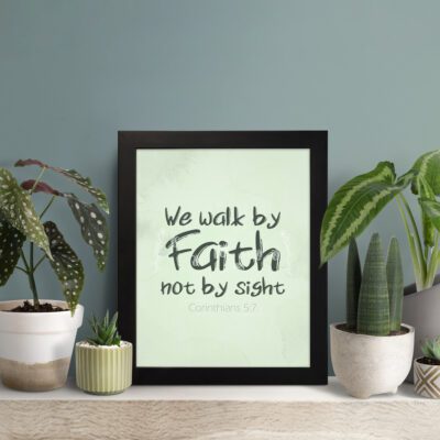 We Walk By Faith Not By Sight Bible Verse Wall Art on a mint green background. displayed on the table in a black frame