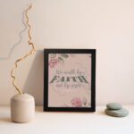 We Walk By Faith Not By Sight Christian Wall Art with pink roses and gray leaves on a soft pink background displayed on the wall in a black frame.