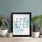 Infidu Psalm 56:4 Christian Wall Art - In God I Have Put My Trust I Will Not Fear with teal text and blue watercolor background. displayed on the table in a black frame