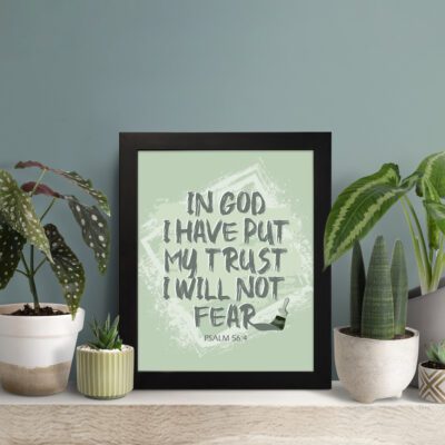 In God I Have Put My Trust, I Will Not Fear Psalm 56:4 bold Christian wall art with green background and brushstroke lettering displayed on the table in a black frame