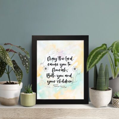 Christian wall art featuring Psalm 115:14 in black cursive on a pastel watercolor background with floral designs. displayed on the table in a black frame