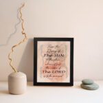 Bible wall art featuring Psalm 113:3 with floral elements and stylish text on a peach background. displayed on the wall in a black frame