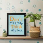 Infidu Don't Think Why, Think Why Not wall art with a red flower design light blue and gray background, and a black frame on the table. Inspiring decor for home offices and workspaces.