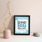 Infidu Dream Big Work Hard Make It Happen wall art with a sky blue and white background and sky blue and black text and black frame displayed on the wall. Inspiring decor for home offices and workspaces.