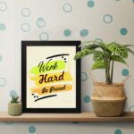 Infidu motivational quotes wall art featuring Work Hard Be Proud on a light white background with light gray flowers and black frame on the table. the inspiring success