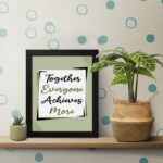 Infidu motivational quotes wall art featuring Together Everyone Achieves More on a light gray and light green background and black frame on the table. the inspiring teamwork