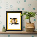 Inspirational quote wall art with "Believe In Yourself" on a white and yellow background and black framed on the table. Perfect for motivating your workspace.