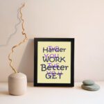 Infidu The Harder You Work The Better You Get wall art with a light sandal background dark blue and violet text and a black frame displayed on the wall. Inspiring decor for home offices and workspaces.