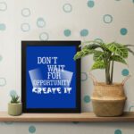 Infidu motivational quotes wall art featuring Don’t Wait For Opportunity, Create It on a blue background and black frame on the table. inspire your workspace