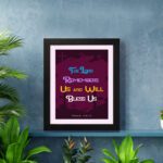 Infidu Bible Wall Art with the text The Lord Remembers Us and Will Bless Us in blue, yellow, and white on a purple background. displayed on the wall in a black frame