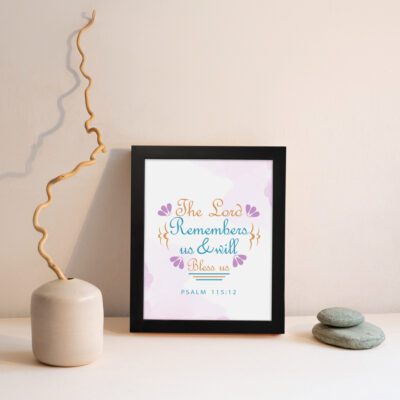 Wall art featuring The Lord Remembers Us And Will Bless Us Psalm 115:12 in pastel colors with leaf accents on a soft background. displayed on the wall in a black frame