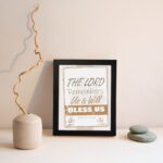 Infidu The Lord Remembers Us And Will Bless Us Psalm 115:12 Bible wall art with elegant text and plant border. displayed on the wall in a black frame