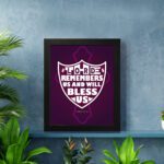 The Lord Remembers Us and Will Bless Us Psalm 115:12 Bible Verse Wall Art in bold white text on a deep purple background. displayed on the wall in a black frame