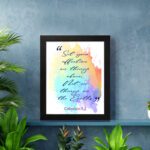 Bible wall art featuring Colossians 3:2 in cursive text on a colorful rainbow background. displayed on the wall in a black frame