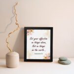 Infidu Bible wall art with Colossians 3:2 in dark brown text, surrounded by peach and beige flowers on a cream background. displayed on the wall in a black frame