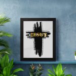 Infidu Jesus Christ Bible Wall Art featuring a black cross and gold lettering on a light gray background. Perfect for home decor. displayed on the wall in a black frame